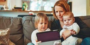 A mom uses a tablet computer with her two small children.