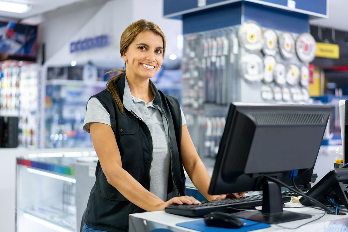 Happy Latin American woman working at the cashier at a hardware store and looking at the camera smiling