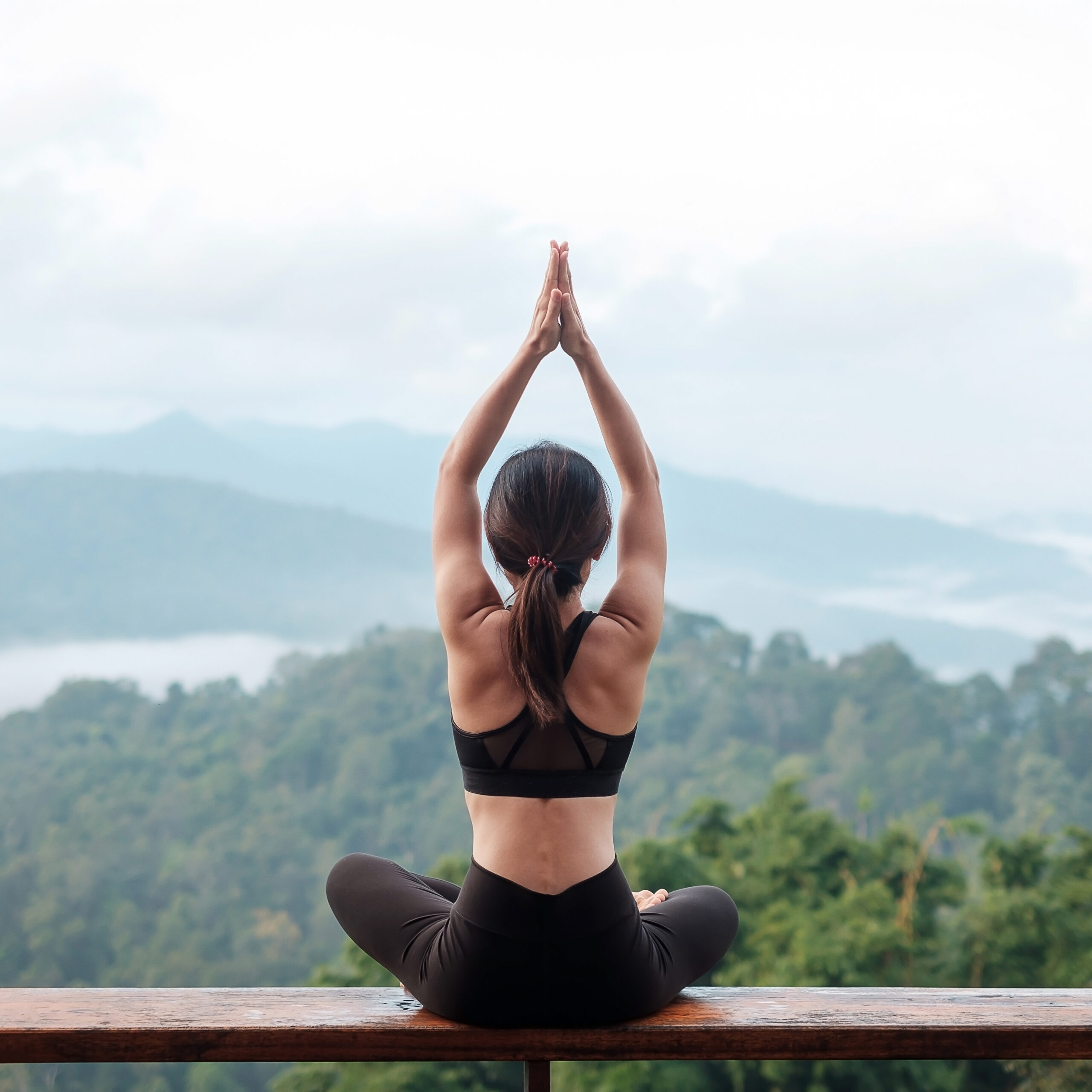 Young woman doing Yoga and stretching muscle in morning, healthy girl meditation against mountain view. wellness, fitness, Vitality, exercise and work life balance concepts