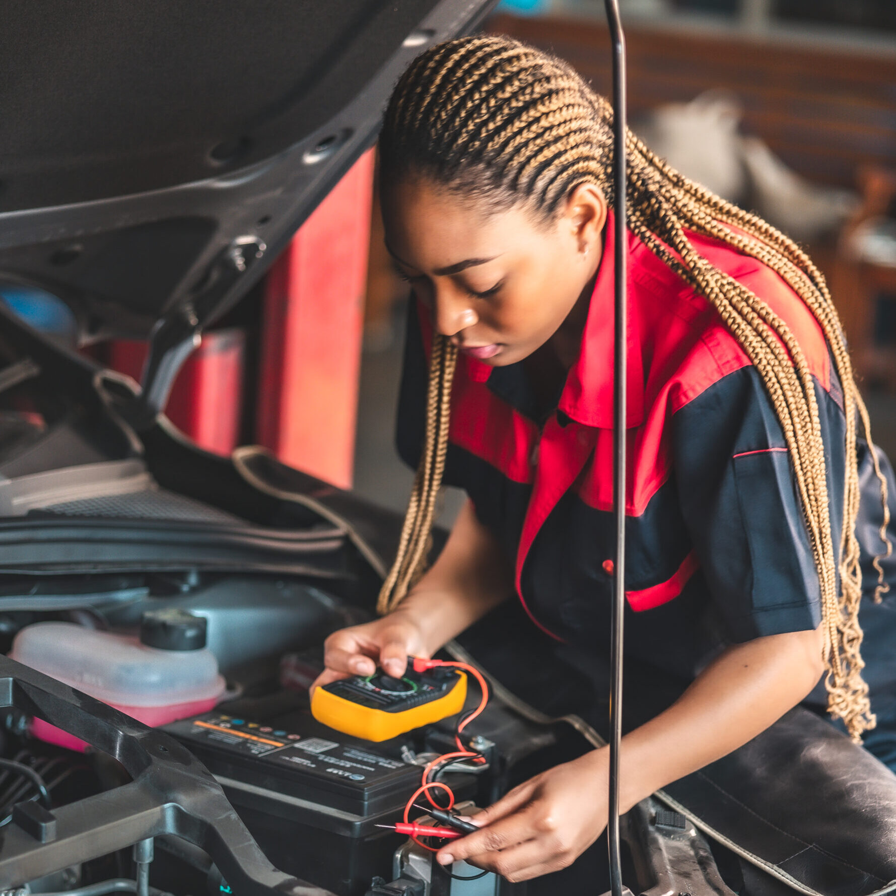 Auto service, repair, maintenance concept. Mechanic checks the car at the service station.African american woman  and asian engineer use tablet check car battery .
